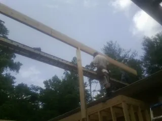 Carpenter setting a ridge beam over a new addition frame — Ice Dam Removal by Roofing Brothers in Dawson